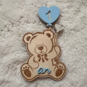 Carte étape bébé bois représentant un ourson tenant deux ballons, l’un en forme de cœur bleu avec le chiffre 1 et l’autre argenté, accompagnée du texte « an »